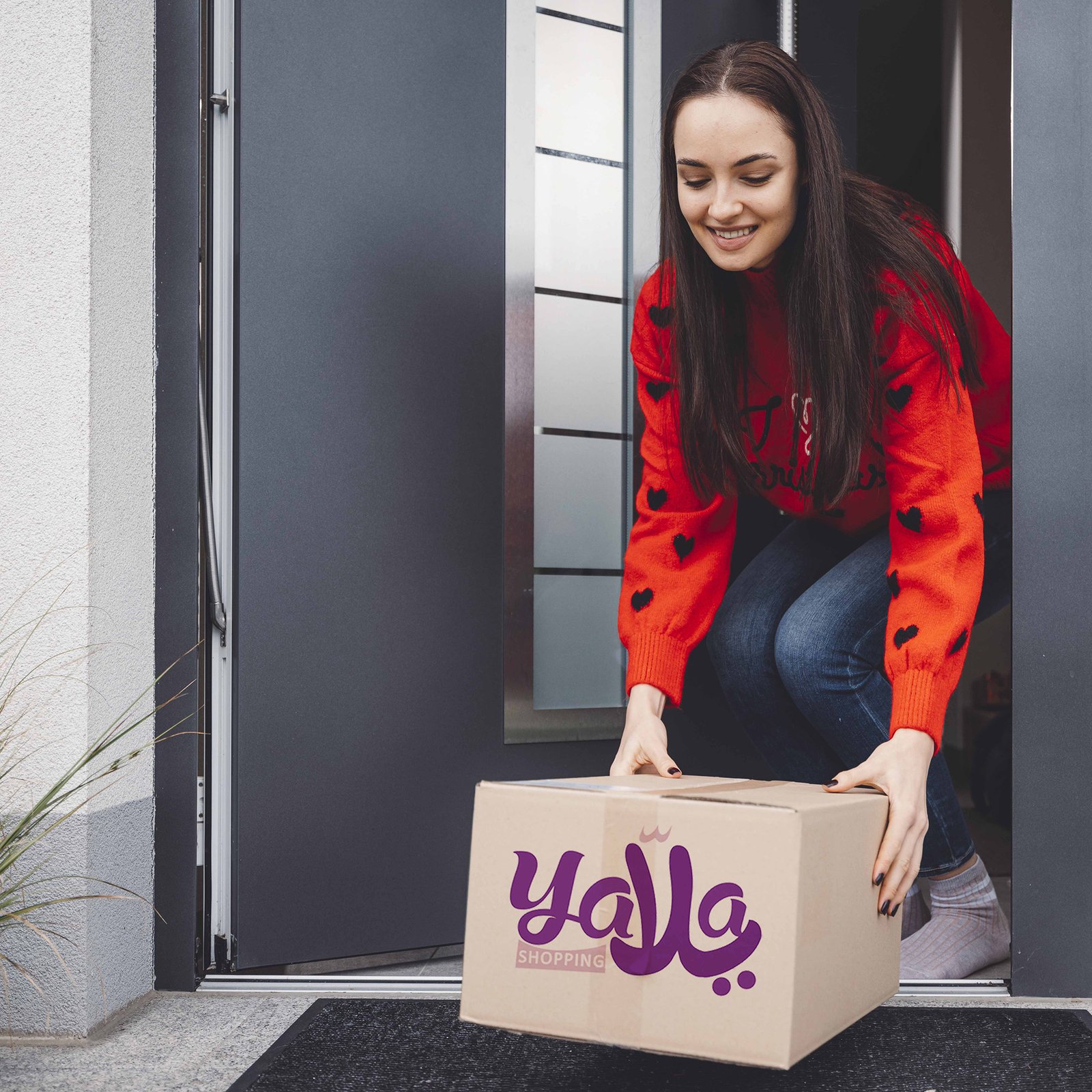 Smiling woman in Christmas spirit picking up a cardboard box at the front door divi-cart-pro-about-1